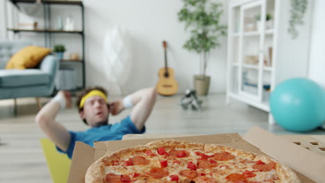 funny man doing workout at home and eating pizza