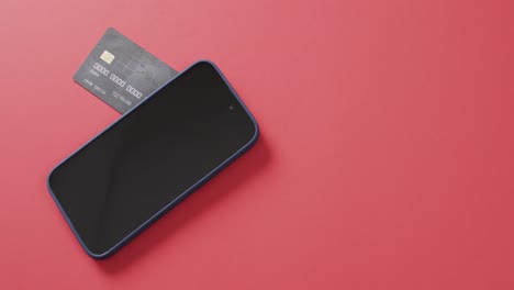 video of smartphone with blank screen, boxes and credit card with copy space on red background