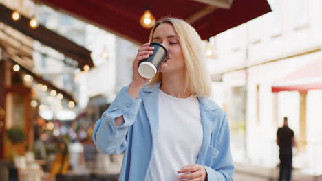 happy woman enjoying morning coffee hot drink and smiling relaxing, taking a break on city street