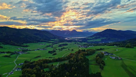 Epic-sunset-light-hits-clouds-with-yellow-streaks-above-gorgeous-European-farm-and-valley