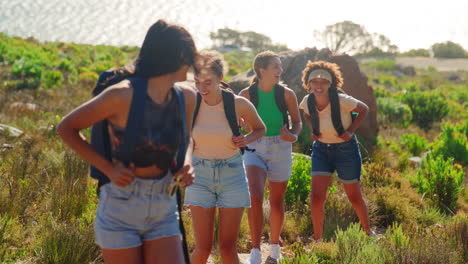 grupo de amigas con mochilas de vacaciones en una caminata por el campo en el camino costero