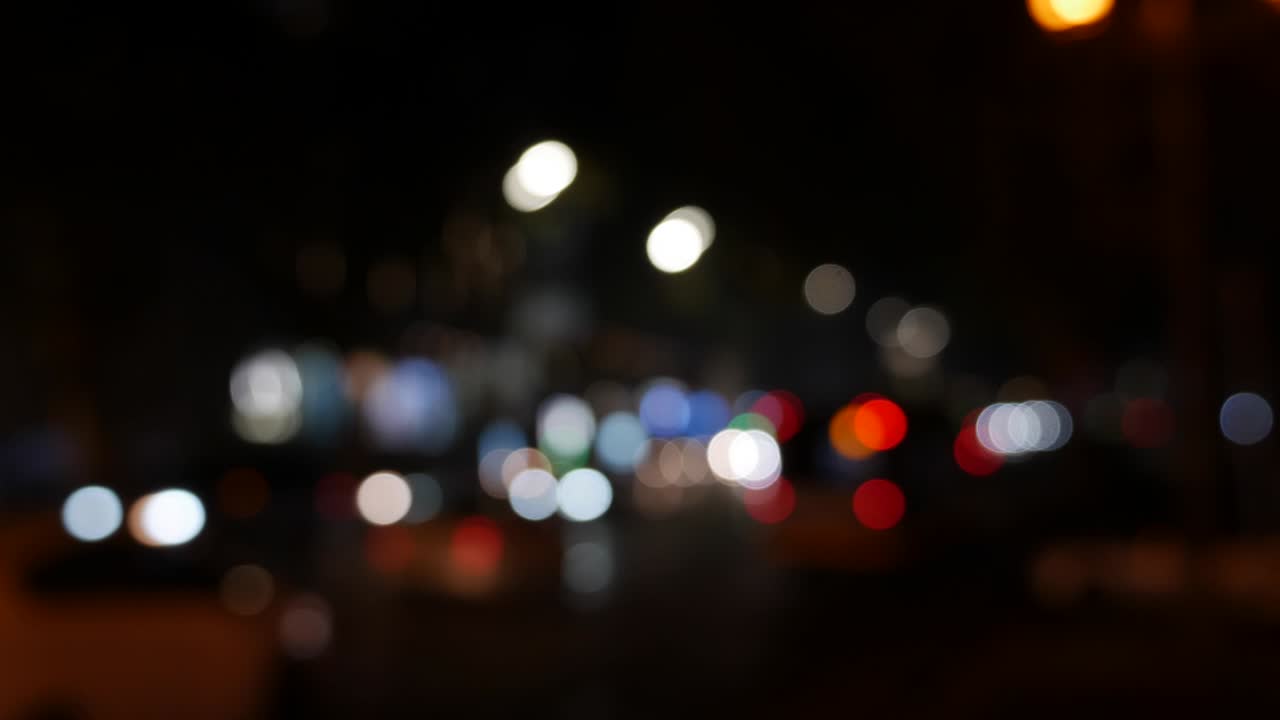 hermoso bokeh brillante en el fondo oscuro borroso por la noche. el redondo bokeh colorido brilla de las luces de los coches en la calle de la ciudad. fuera de foco con borroso. luces de la ciudad sin enfoque. bokeh de tráfico. concepto abstracto