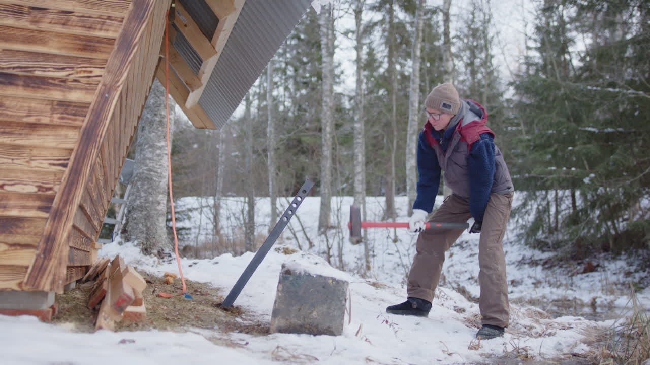 Woman hits huge steel post into ground with sledgehammer to secure wooden cabin