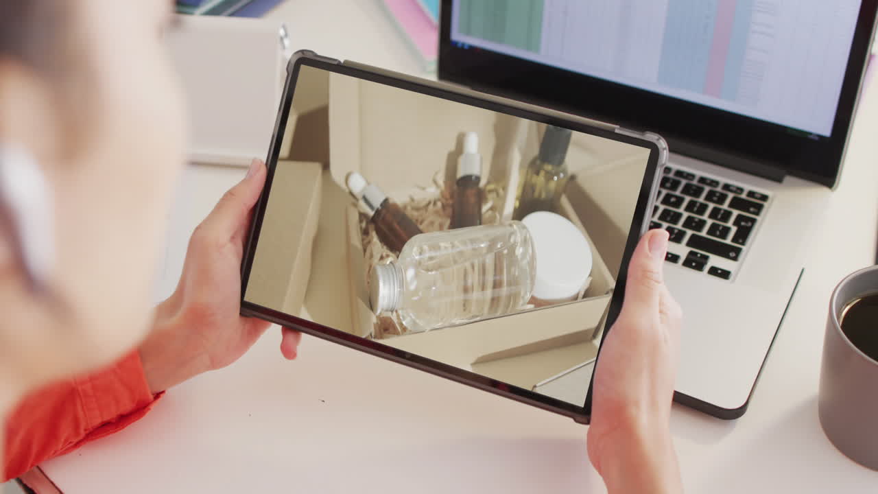 mujer caucásica en el escritorio usando tableta, compras en línea de productos de belleza, cámara lenta