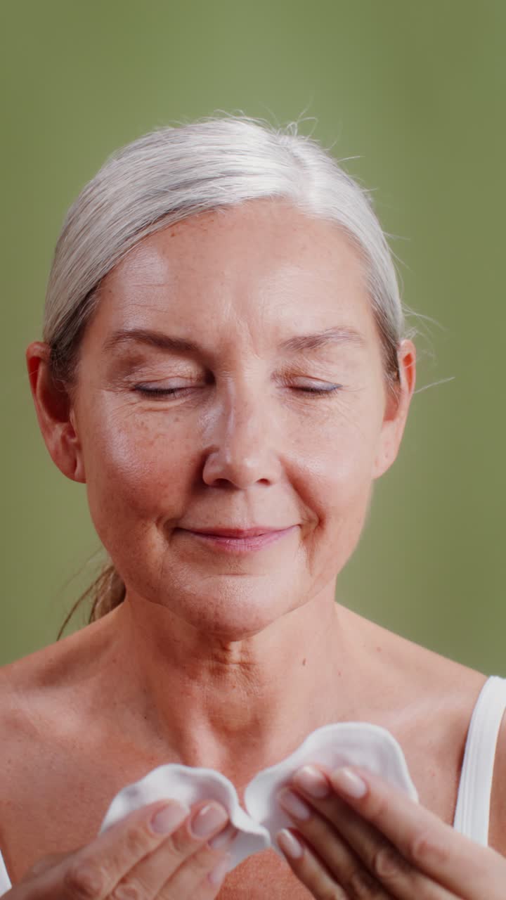 Middle-aged woman using cotton pads for skin care