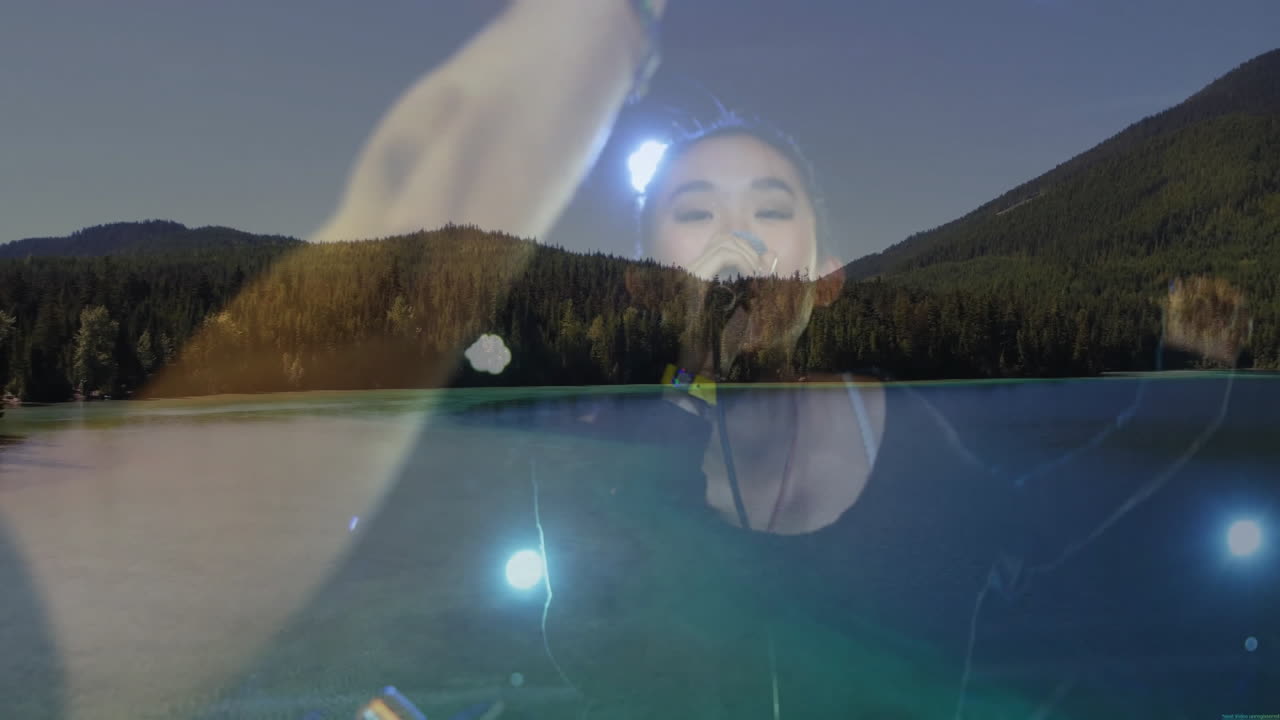woman singer performing music on stage using mic overlaying mountain lake showing blue spotlights