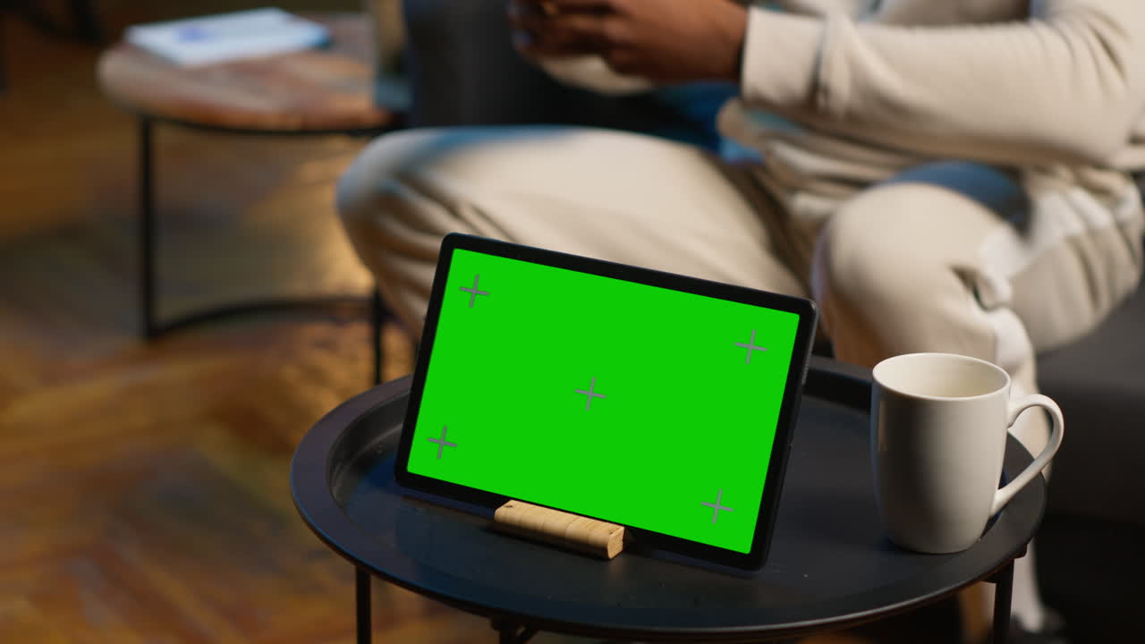 freelancer negro con un dispositivo de pantalla verde en su moderno apartamento de moda, espacio de alta gama decorado con plantas de interior y luces de neón. joven adulto utiliza muebles frescos en casa. cámara a.