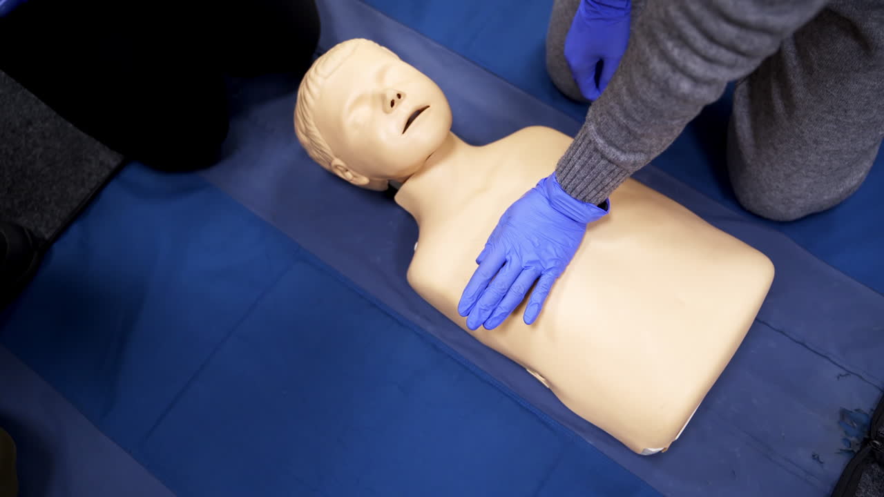 Training on a medical mannequin doll. Learning to do chest compression on a dummy. First aid cardiopulmonary resuscitation training. Top view.