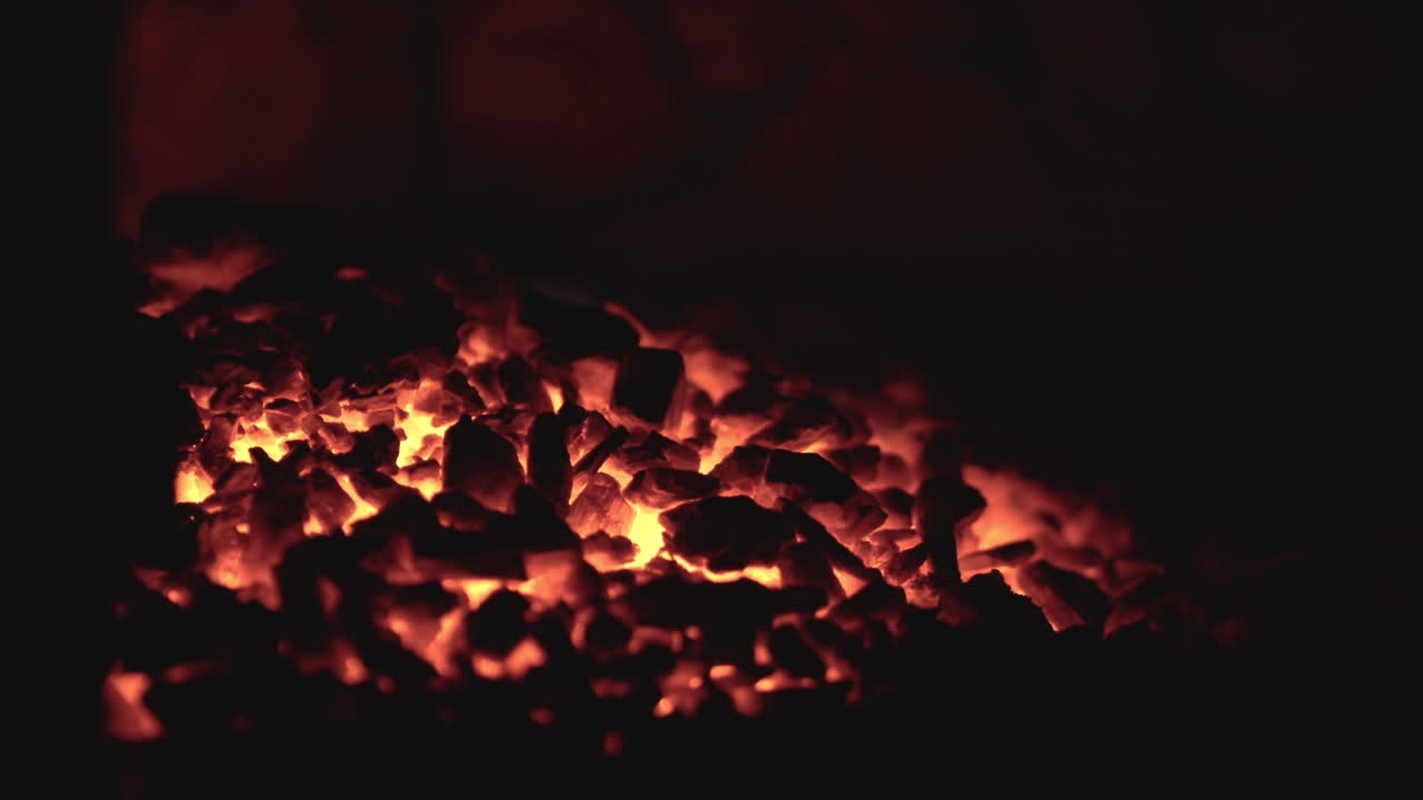 Fiery coals in dark stove, nighttime heat source close-up