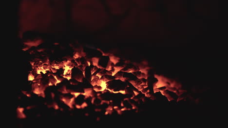 fiery coals in dark stove, nighttime heat source close-up