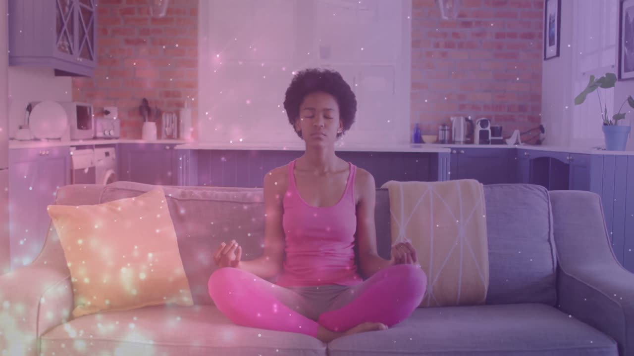 animación de puntos de luz sobre una mujer afroamericana practicando yoga y meditando en casa