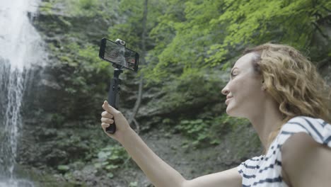 woman taking a video of a waterfall