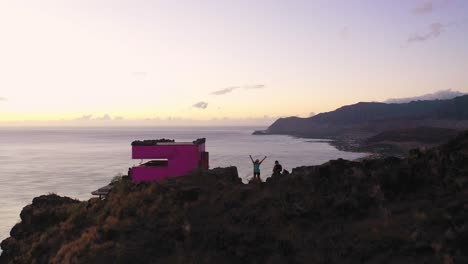 aerial shot flying over puu o hulu mountain in hawaii and two hikers waving at camera from the top. dolly in