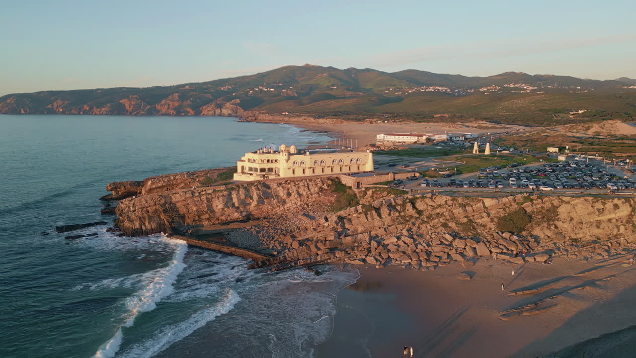 Aerial view ocean rolling sand beach with touristic complex. Clear sky evening