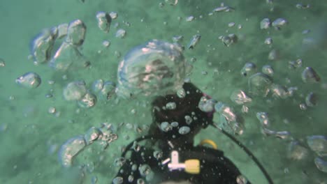 underwater-shot-of-a-diver-seen-from-above-blowing-out-air-bubbles