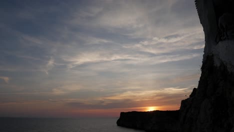 sunset view over the sea at cova d'en xoroi with a dramatic cliffside silhouette