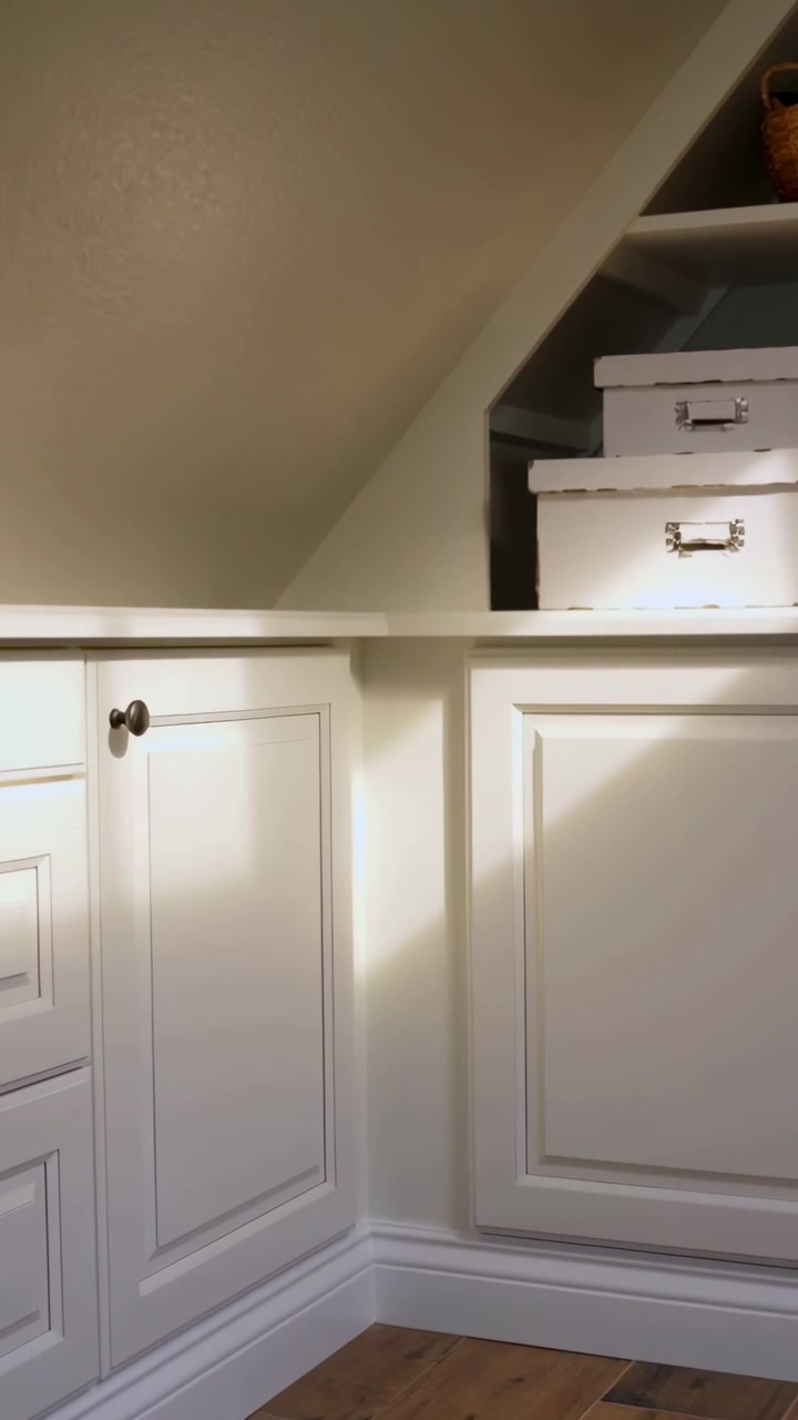 Video vertical: Cámara haciendo un paneo en un loft mientras la luz se desplaza sobre un armario blanco con cajas.
