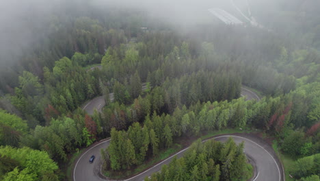 Trucks driving on winding roads in the Romanian mountains surrounded by fog and lush forests