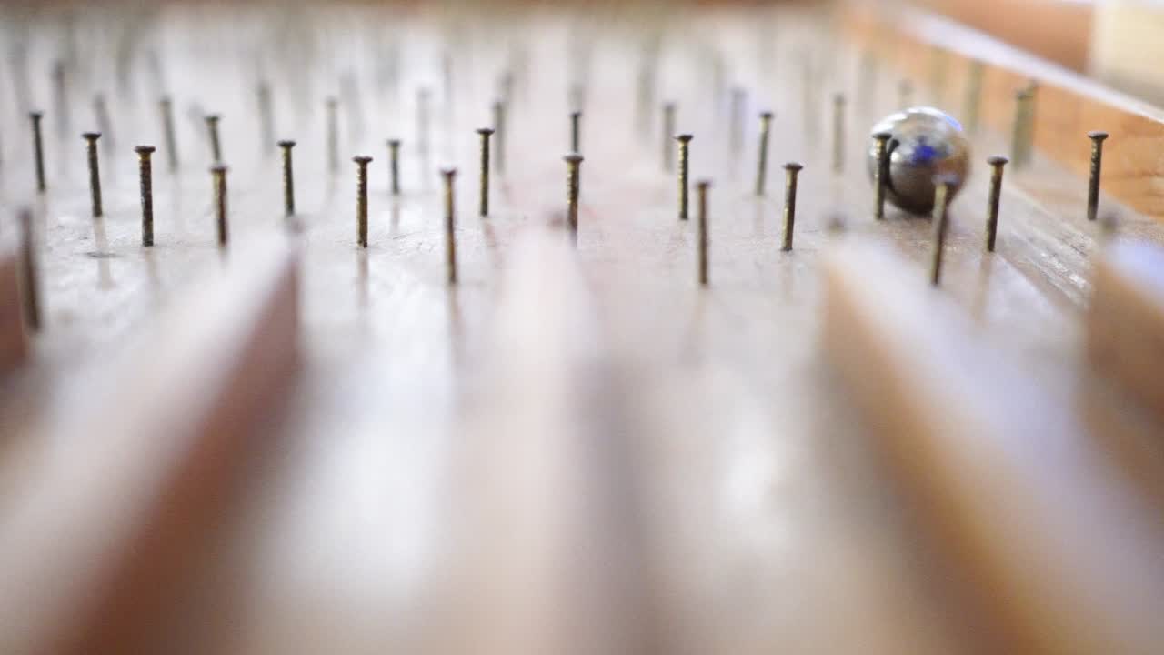 나무로 만든 핀볼 테이블 위에서 유리 구슬이 핀볼테이블 위로 굴러 내려온다.