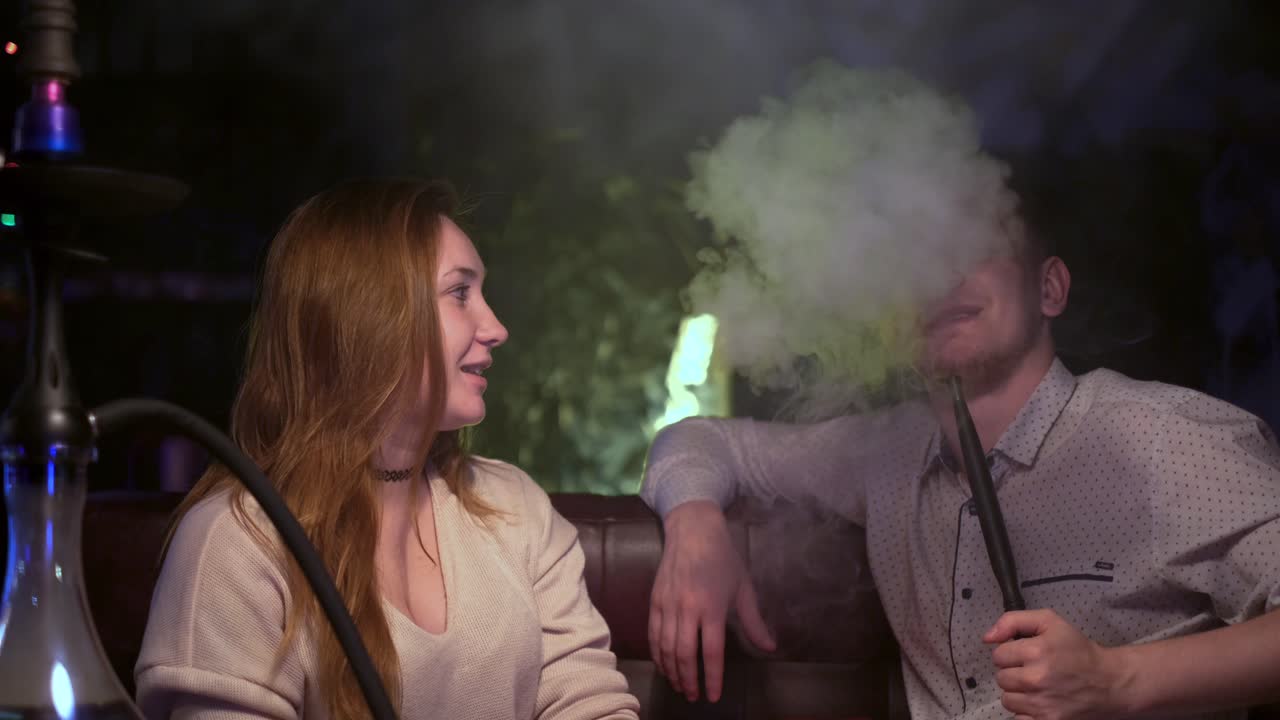 una pareja relajándose con un narguile.