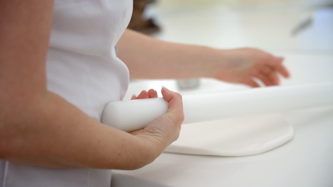 Donna in pasticceria che stende la ghiaccia reale per la decorazione di torte.