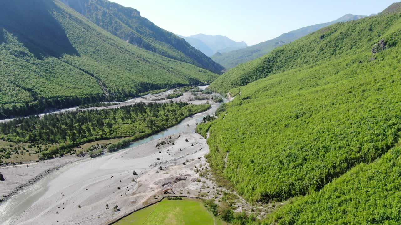 drone vista en albania en los alpes volando sobre un río de cristal con suelo rocoso con bosque verde en los lados en el