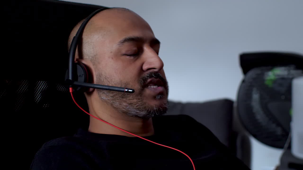 Asian Indian Working From Home Having Online Conversation Wearing Headset And Swivelling In Chair