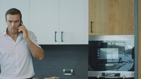 business man talking cell phone on kitchen. man having telephone call in house.