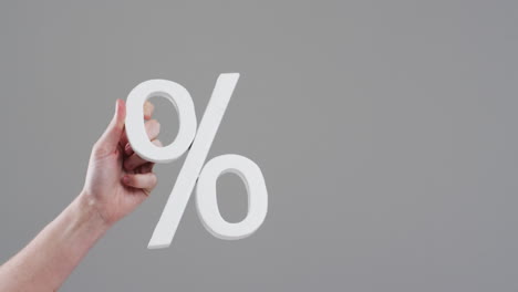 video of hand of caucasian woman holding white percent sign with copy space against grey background