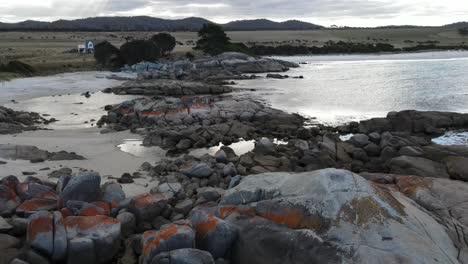 Drone-aerial-pan-down-on-rocky-beach-cloudy-day