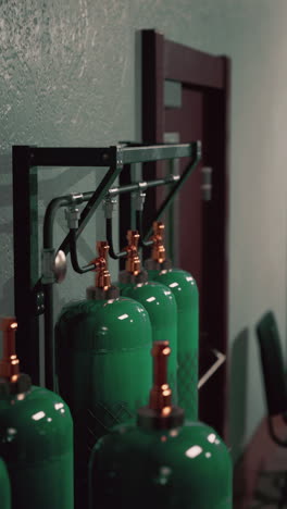 green gas cylinders mounted on a rack in a room