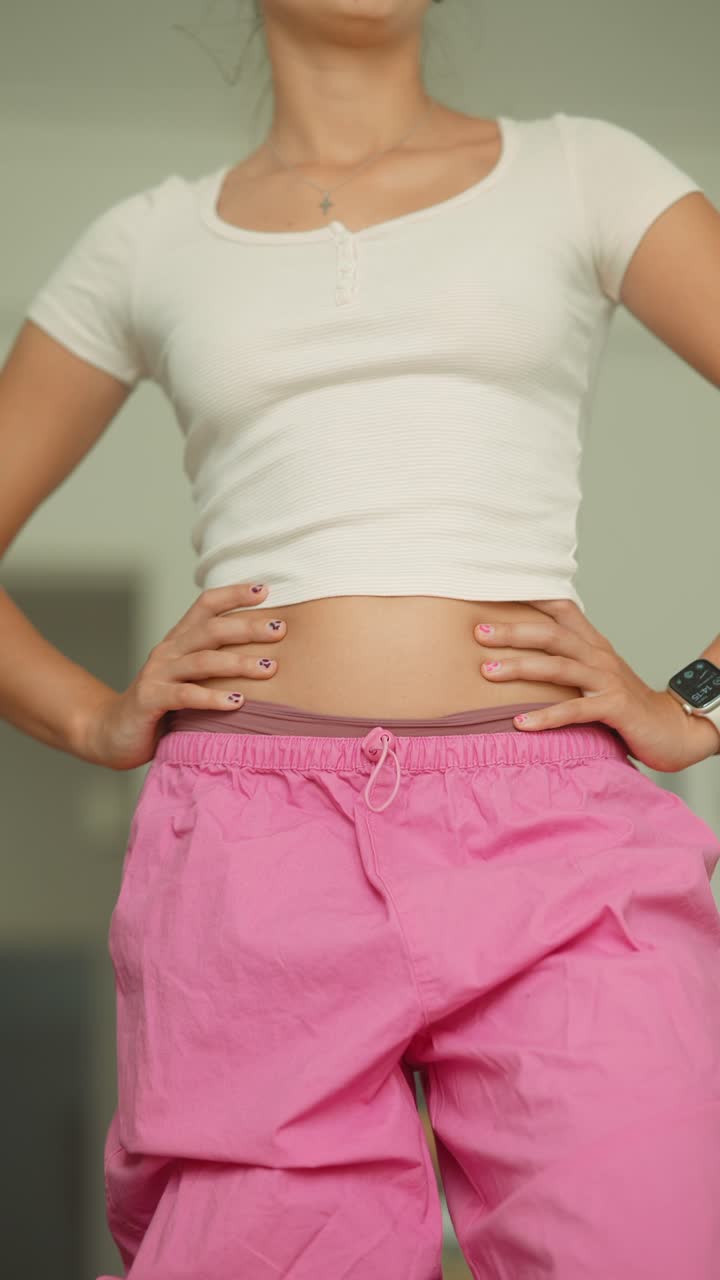 Donna con pantaloni rosa e top corto bianco