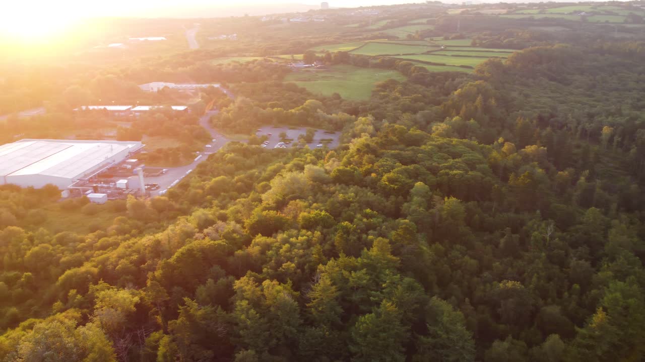 vista aérea del amanecer de un almacén industrial y una autopista con bosque y lago