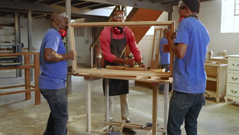 african american male carpenter measuring, marking plank in workshop inspecting new frame alignment
