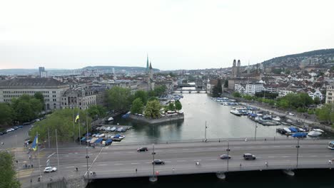 Vista-Aérea-Sobre-El-Río-Limmat-Y-El-Puente-Quaibürcke-Con-Banderas-Ucranianas-Y-Coches-Cruzando,-Zurich,-Suiza