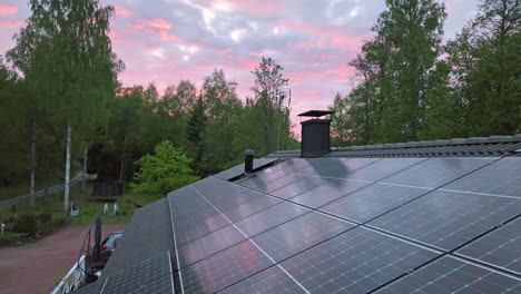 dramatic cloudy sunset sky above a house roof with solar cells - aerial view