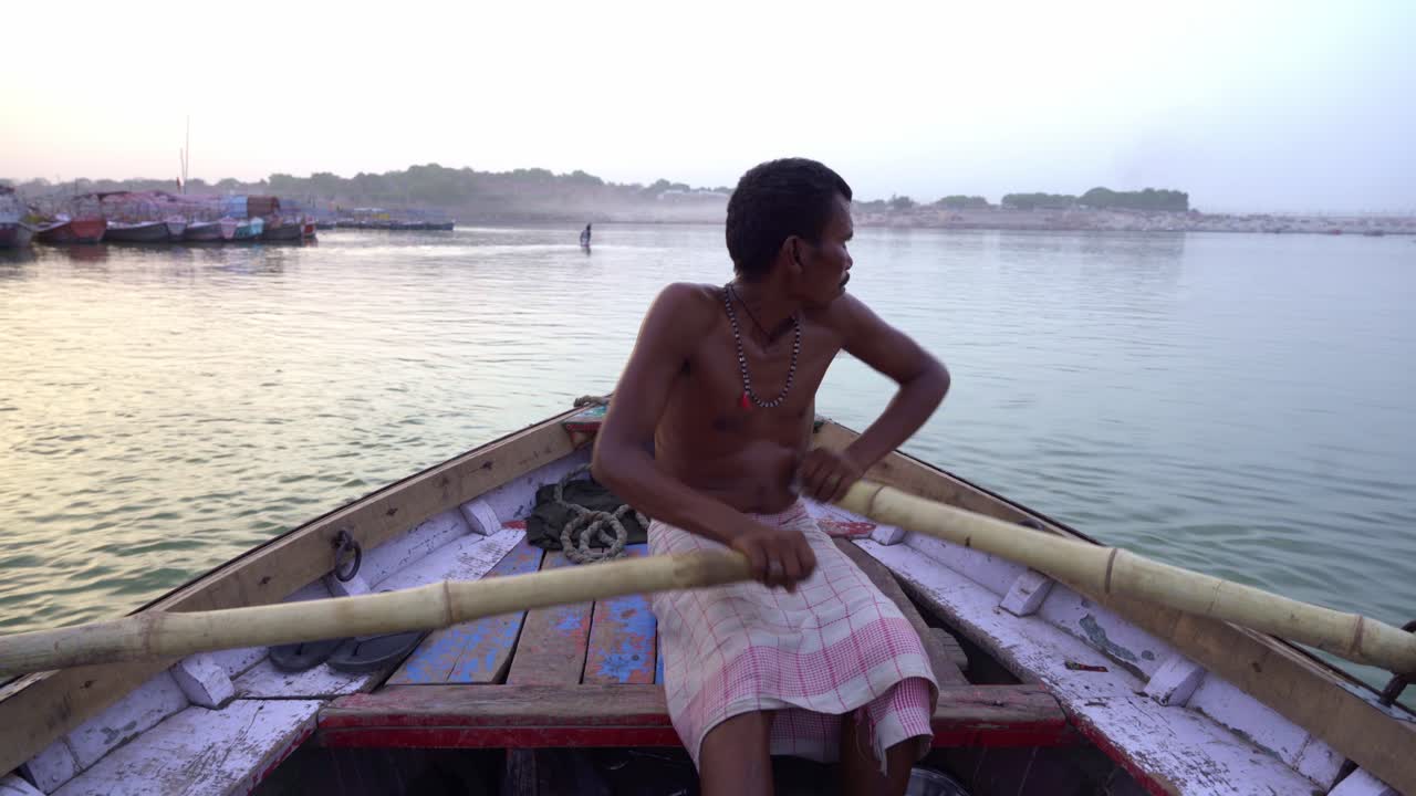 Man Rowing a Traditional Boat on a River at Sunrise