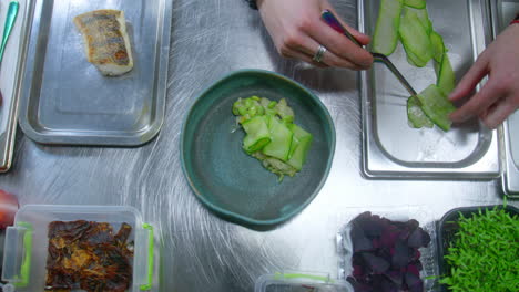 chef preparing gourmet fish dish with vegetables and microgreens