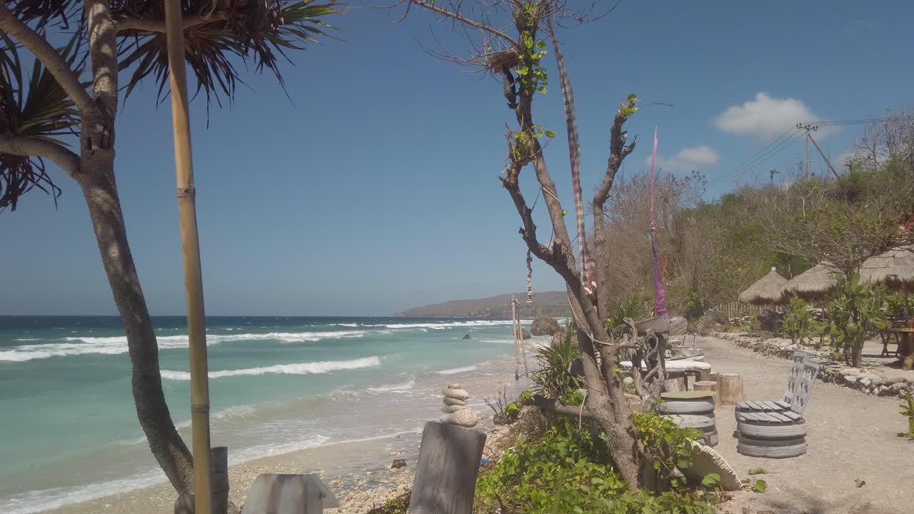 Beautiful white sandy beach and blue ocean in Bali Indonesia, Nusa Penida exotic island. Palm trees and rural village.