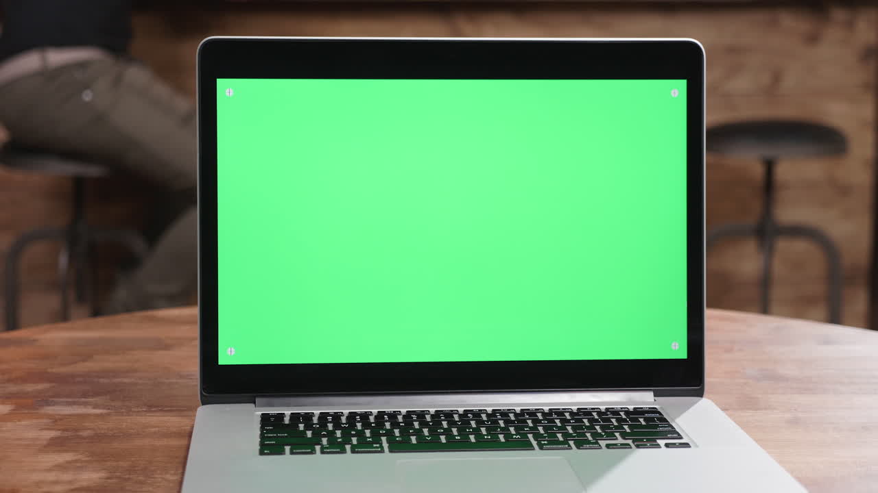 Laptop with green screen on wood table