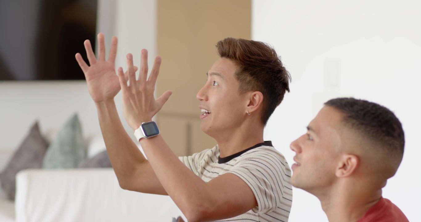Diverse male pals reacting to screen as African American man gesturing and Asian man raising tablet