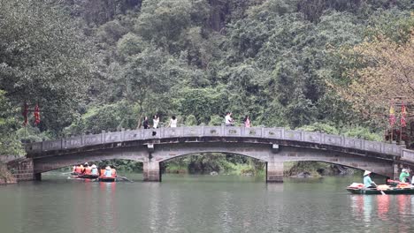 colorful boats moving under an old stone bridge