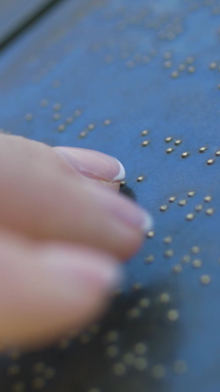 Primo piano di una mano che tocca i punti Braille su una superficie