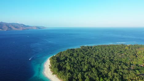 Beautiful-seascape-wallpaper-with-blue-sea-bordered-by-bright-sky,-mountains-and-green-tropical-island-cape-in-Indonesia