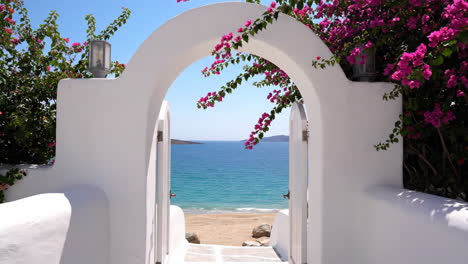 white archway leading to a secluded beach with bougainvillea