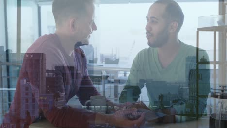 animation of cityscape over diverse male couple drinking coffee and talking