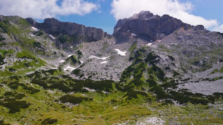 Karadağ'daki Durmitor dağ silsilesinin kayalık zirvelerinin ve yeşil yamaçlarının görkemli, geniş açılı havadan görünümü.