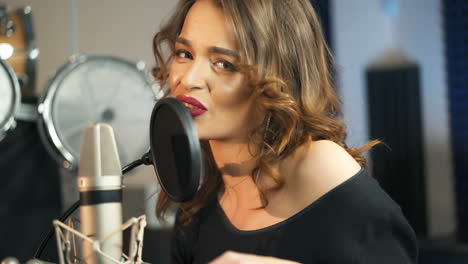 young female singer recording album in the professional studio. woman singing a song in music recording studio.