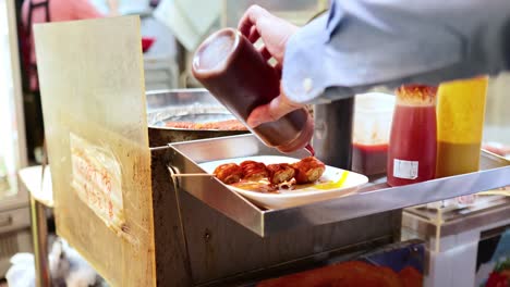 vendedor preparando comida con salsas en un puesto callejero