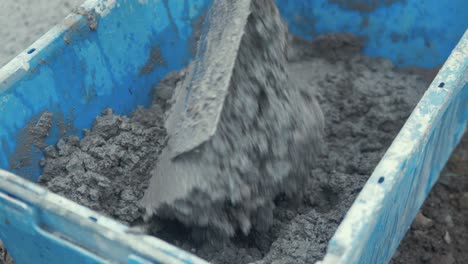 using shovel mixing cement in bucket close up slow motion